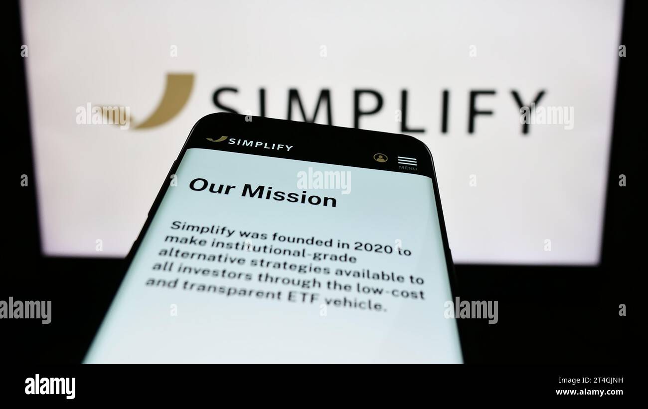 Mobile phone with website of US investment company Simplify Asset Management Inc. in front of business logo. Focus on top-left of phone display. Stock Photo