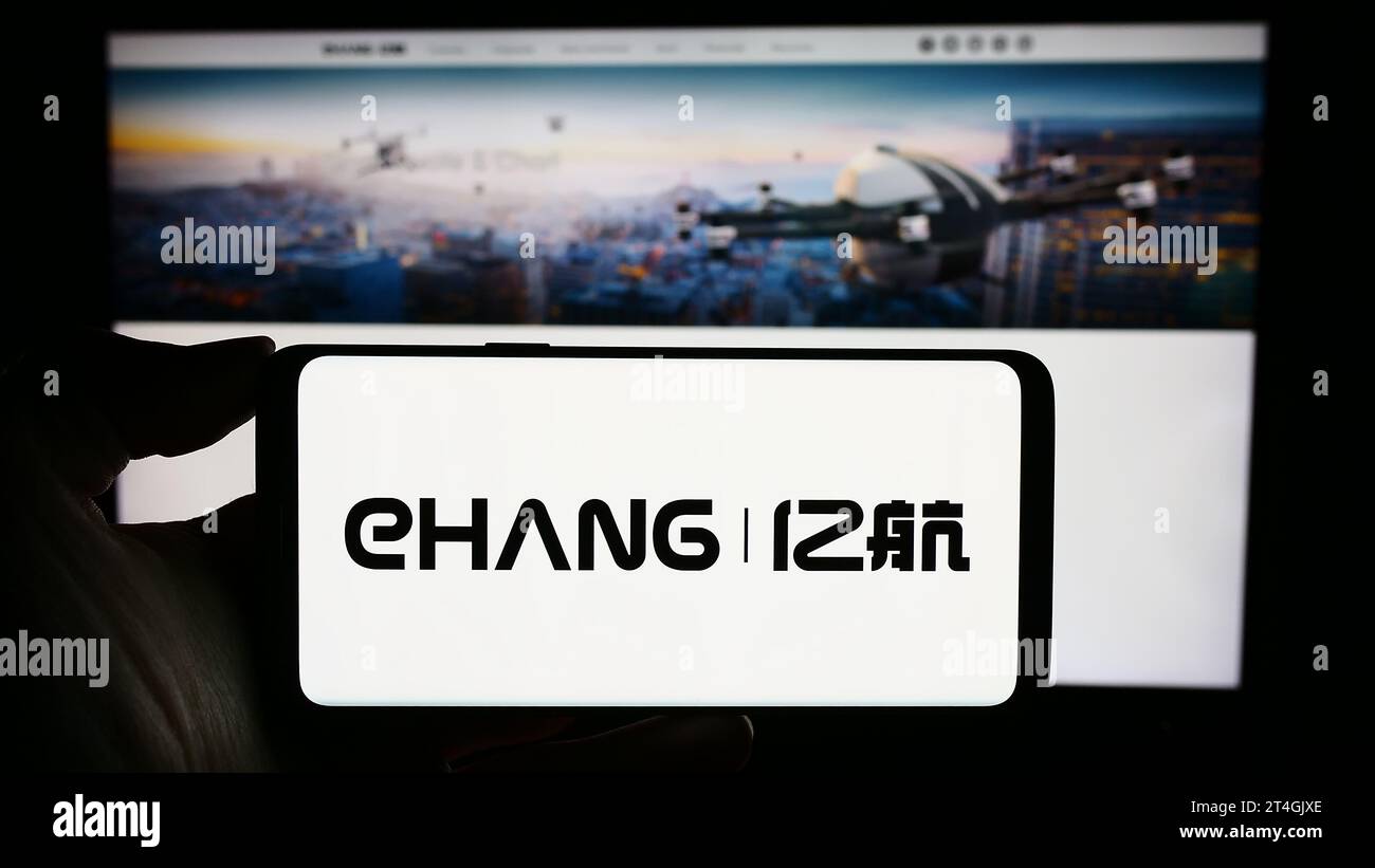 Person holding mobile phone with logo of Chinese aviation company EHang Holdings Limited in front of business web page. Focus on phone display. Stock Photo