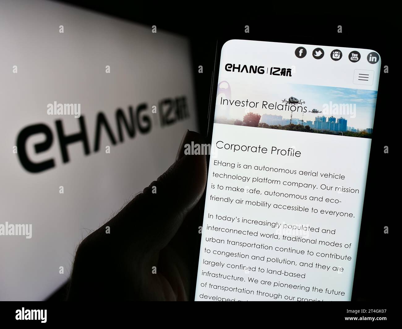 Person holding cellphone with webpage of Chinese aviation company EHang Holdings Limited in front of logo. Focus on center of phone display. Stock Photo