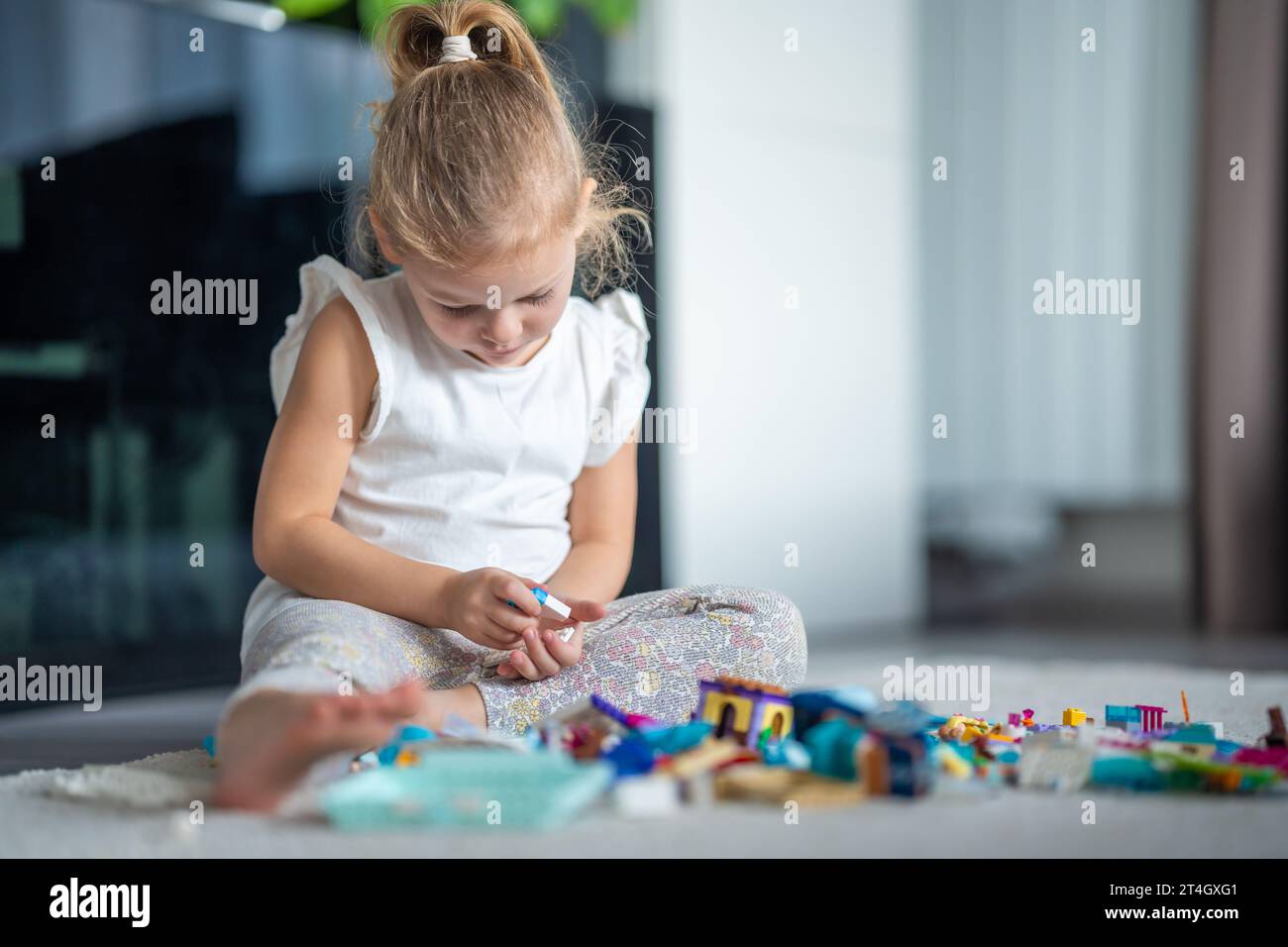 Little girl playing with small constructor toy on the floor in home ...