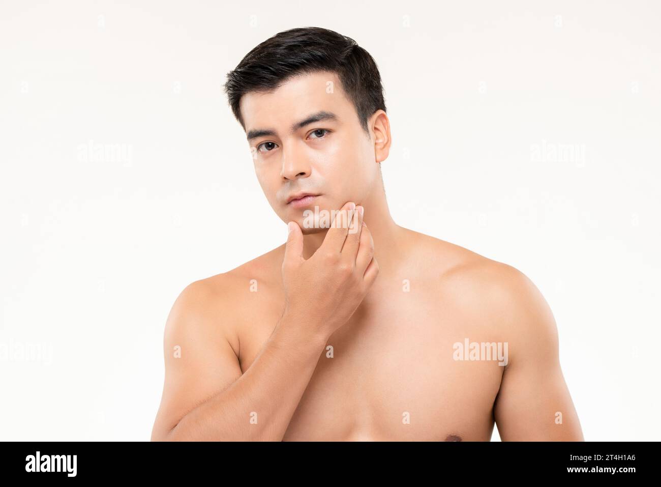 Handsome man touching his face checking for skin problems and wrinkles in white isolated background Stock Photo