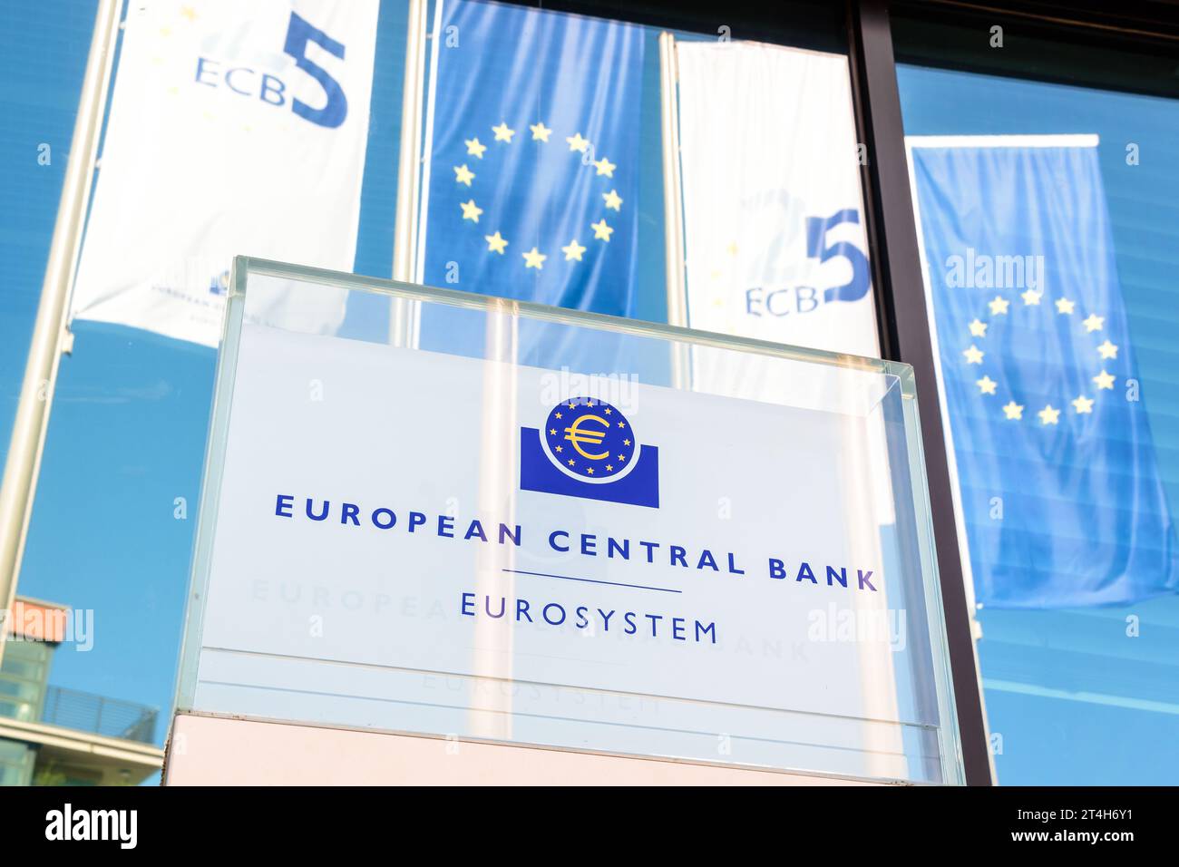 Low angle view of the sign of the European Central Bank in Frankfurt, Germany, with banners of the European Union in the background. Stock Photo