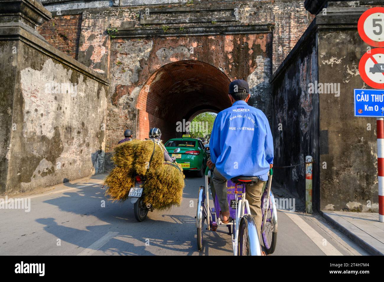 A tricycle taxi cyclist pedals a tourist along the roads in Hue city, Vietnam. Stock Photo