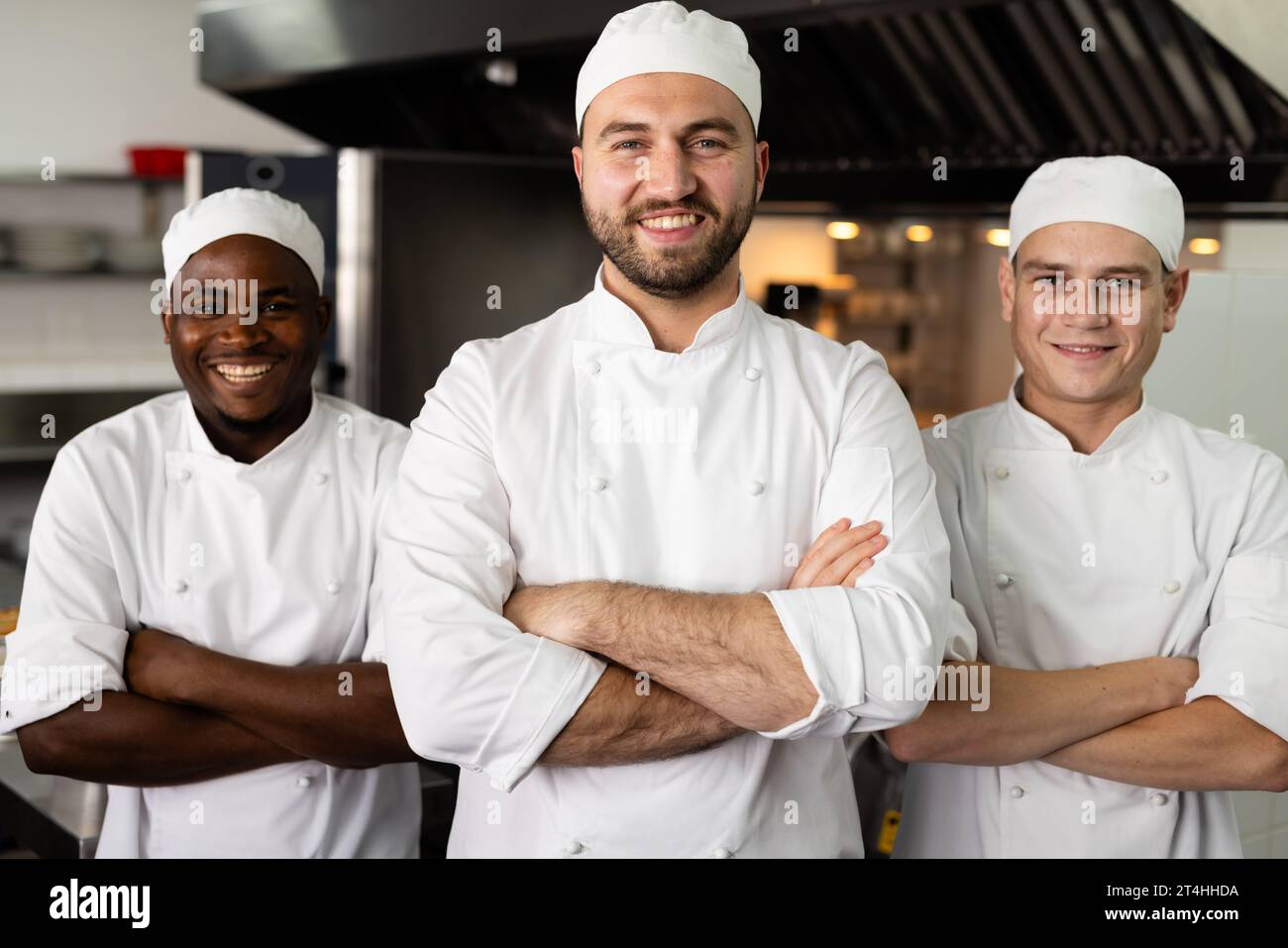 Portrait of smiling diverse male chefs with arms crossed standing side by side in commercial kitchen Stock Photo