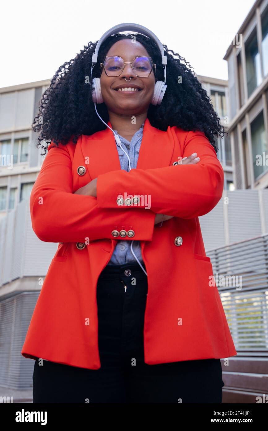 Vertical Single close up of smiling African American businesswoman standing looking at camera with arms crossed. Stock Photo