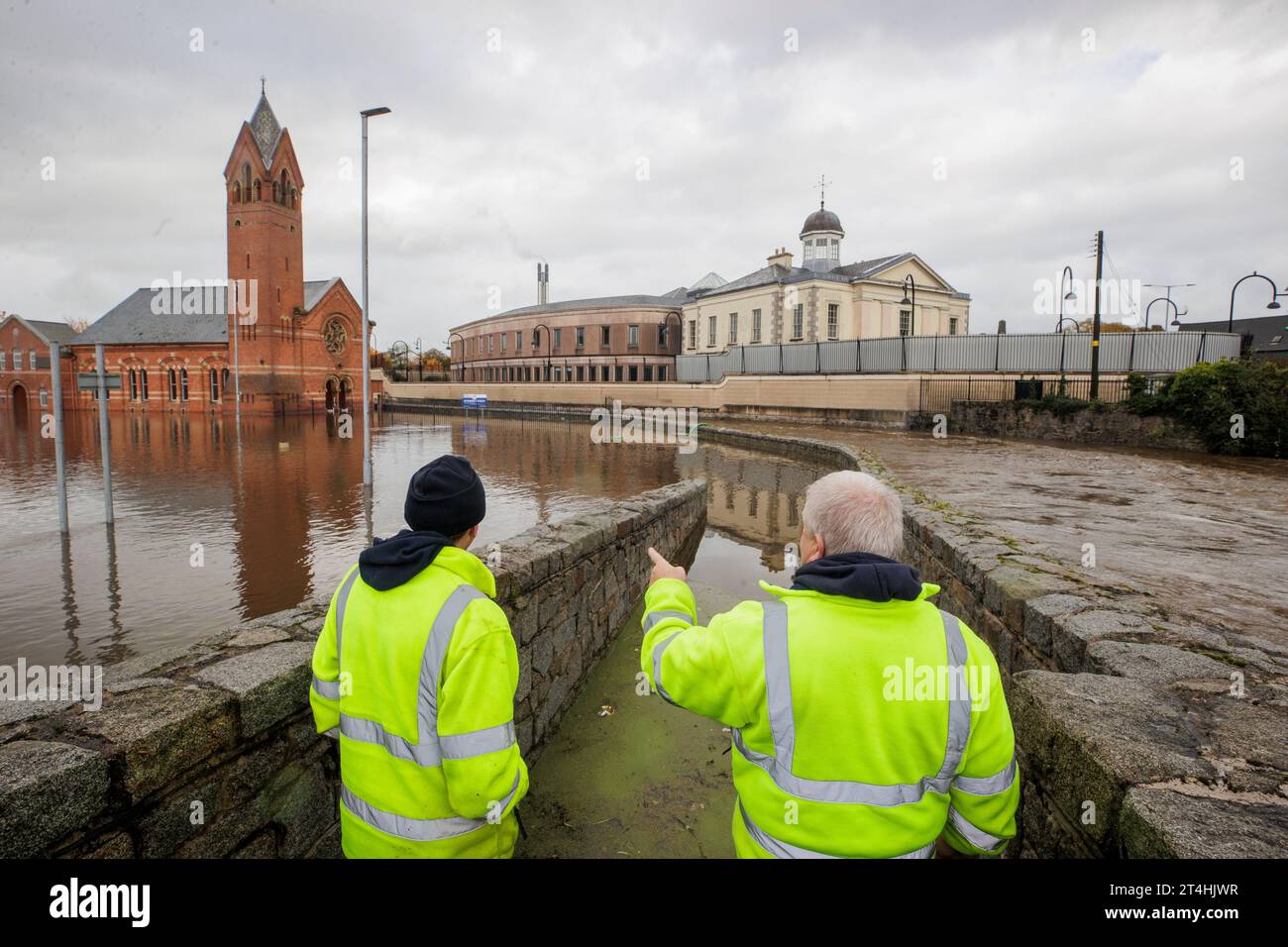 DFI workers look at the flooded water in a car park beside Riverside