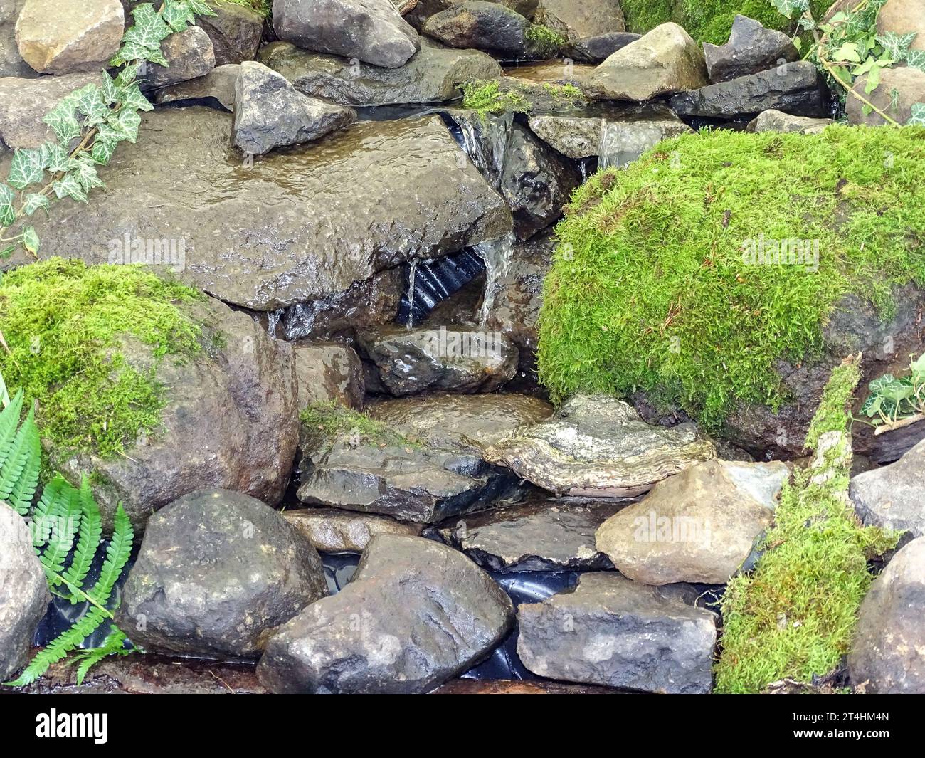 Artificial mini waterfall with stones and vegetation Stock Photo