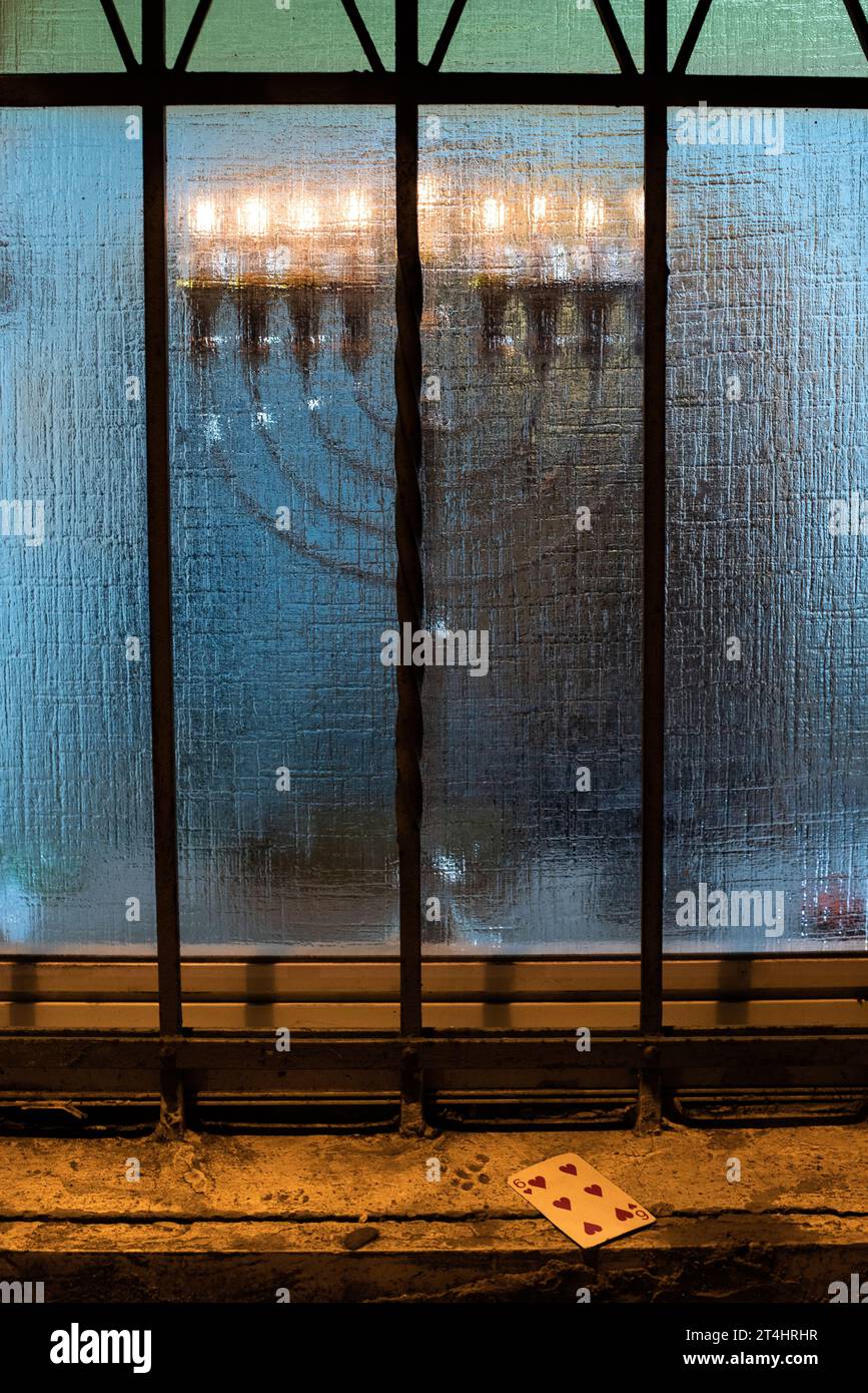 A Hanukkah menorah seen through blue frosted glass window burns