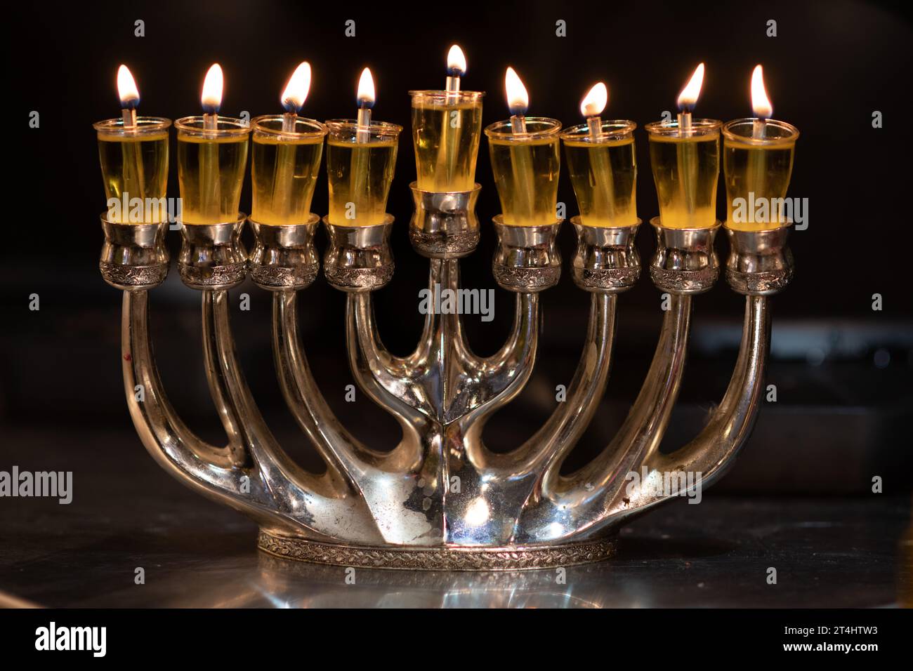 A silver Hanukkah menorah with eight candles burns brightly during the