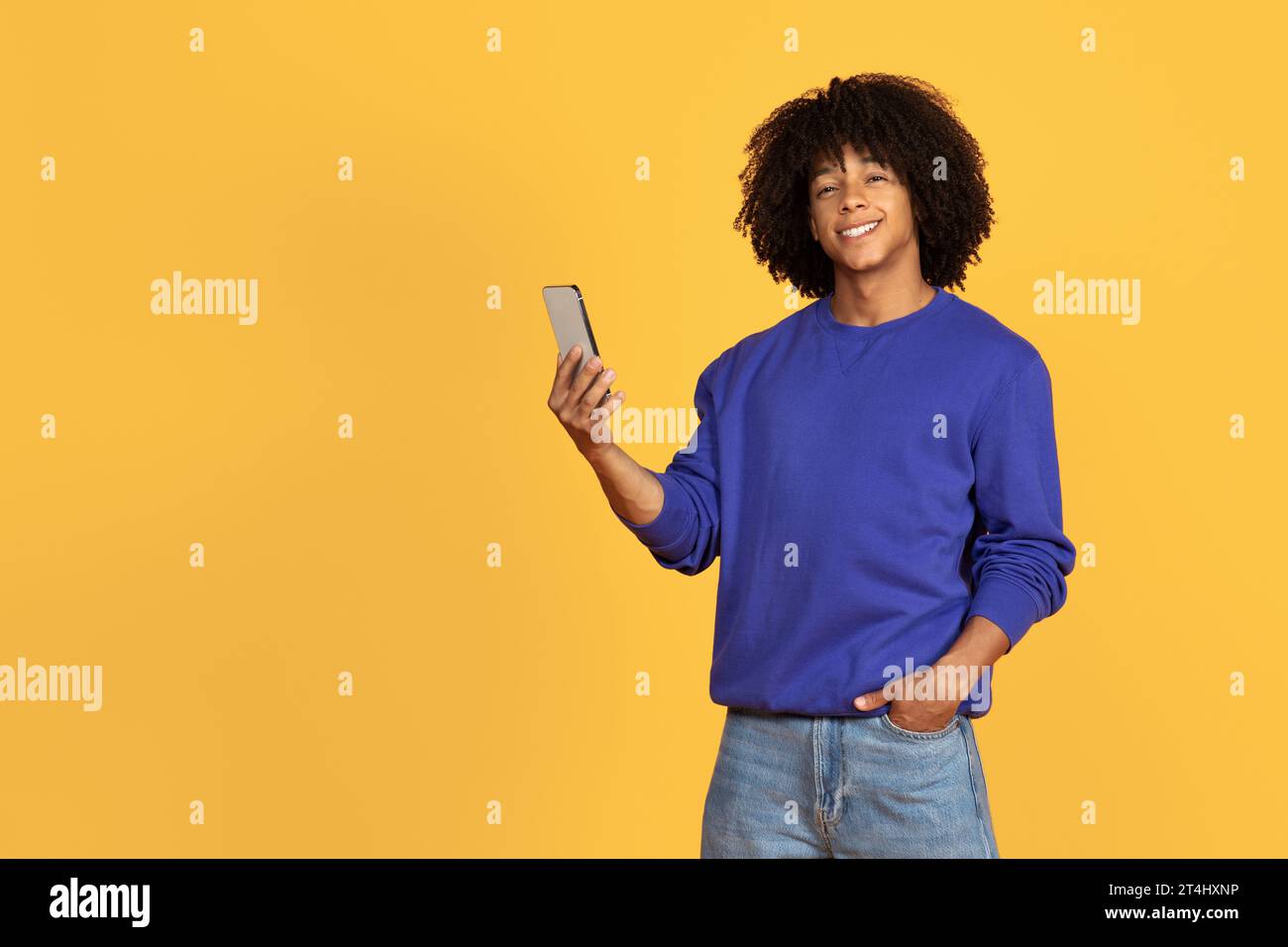 Happy Young Black Guy Using Mobile Phone And Smiling At Camera Stock Photo
