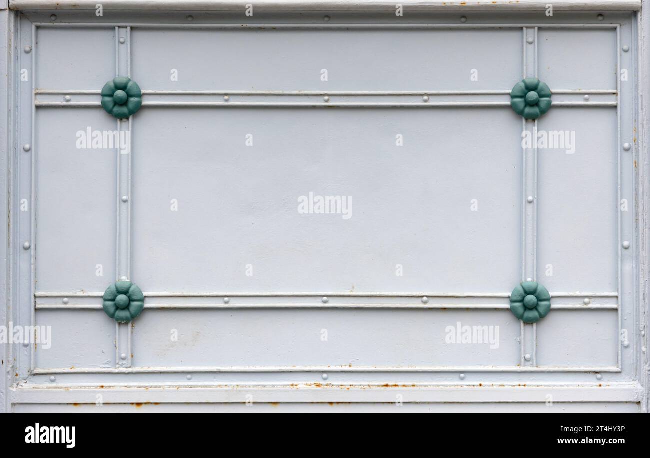 Forged decor with rectangle frame and green flowers on a white steel wall, front view, background photo texture Stock Photo
