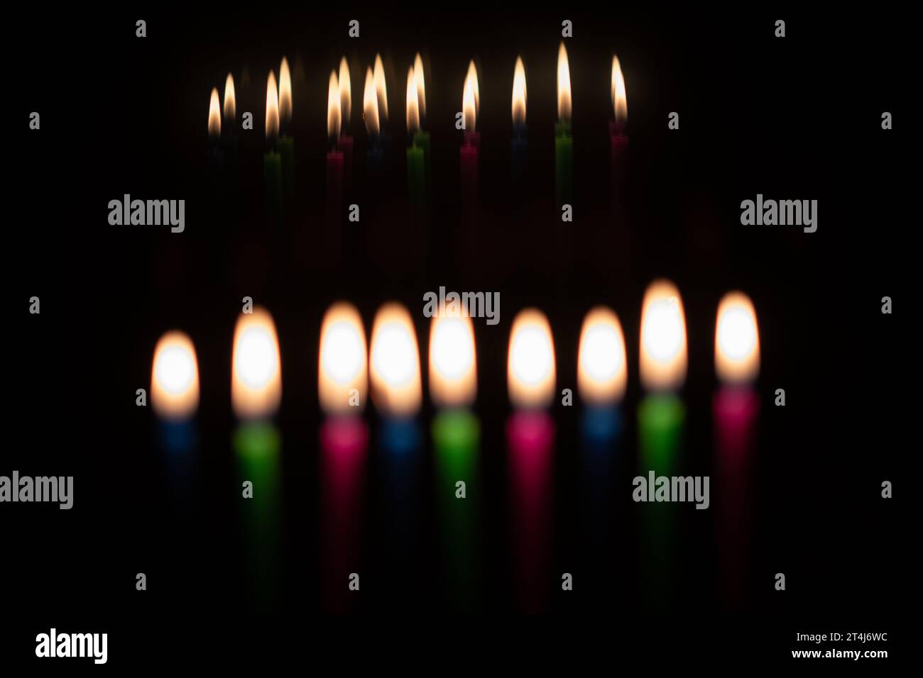 Multicolored, wax Hanukkah candles burn in a menorah during