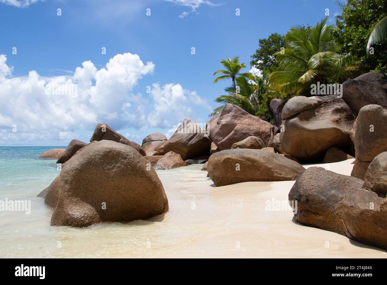 Beautiful palm fringed beach, turquoise waters and granite boulders at the luxury hotel and resort Constance Lemuria, Praslin, Seychelles, Indian Ocean Stock Photo