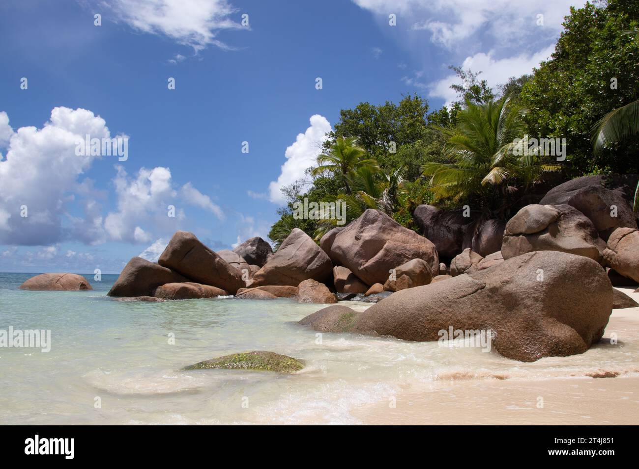 Beautiful palm fringed beach, turquoise waters and granite boulders at the luxury hotel and resort Constance Lemuria, Praslin, Seychelles, Indian Ocean Stock Photo