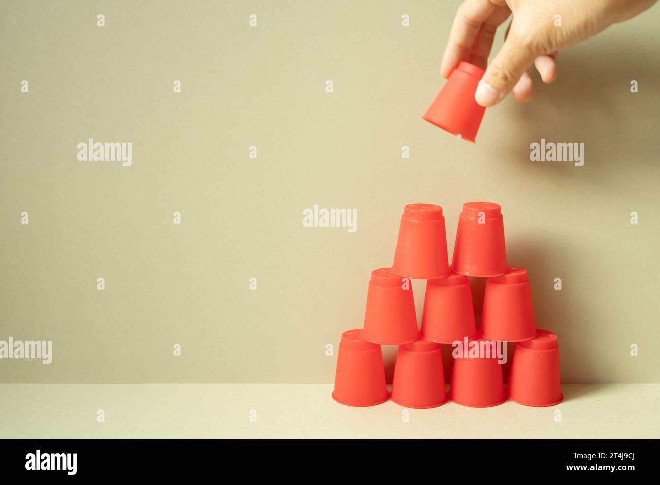 Pyramid of red plastic cups on desk. khaki beige background. teamwork ...