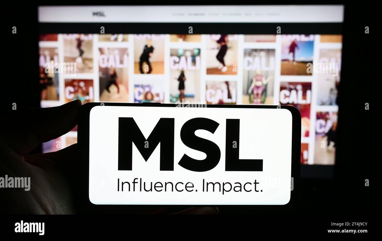 Person holding smartphone with logo of French public relations company MSLGROUP in front of website. Focus on phone display. Stock Photo