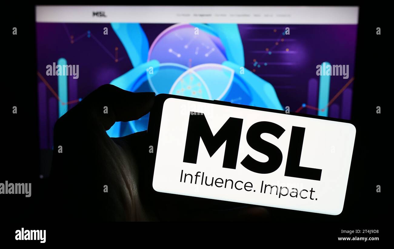 Person holding cellphone with logo of French public relations company MSLGROUP in front of business webpage. Focus on phone display. Stock Photo
