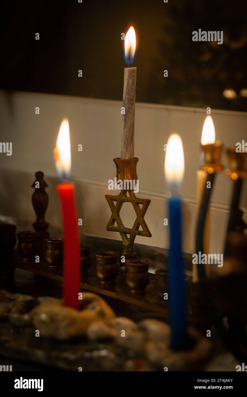 Multicolored, wax Hanukkah candles burn in a menorah during