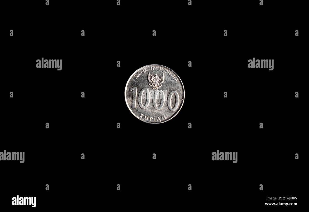 Uang koin Indonesia seribu 1000 rupiah, Indonesian one thousand rupiah coin with black back ground, top view, isolated. Stock Photo