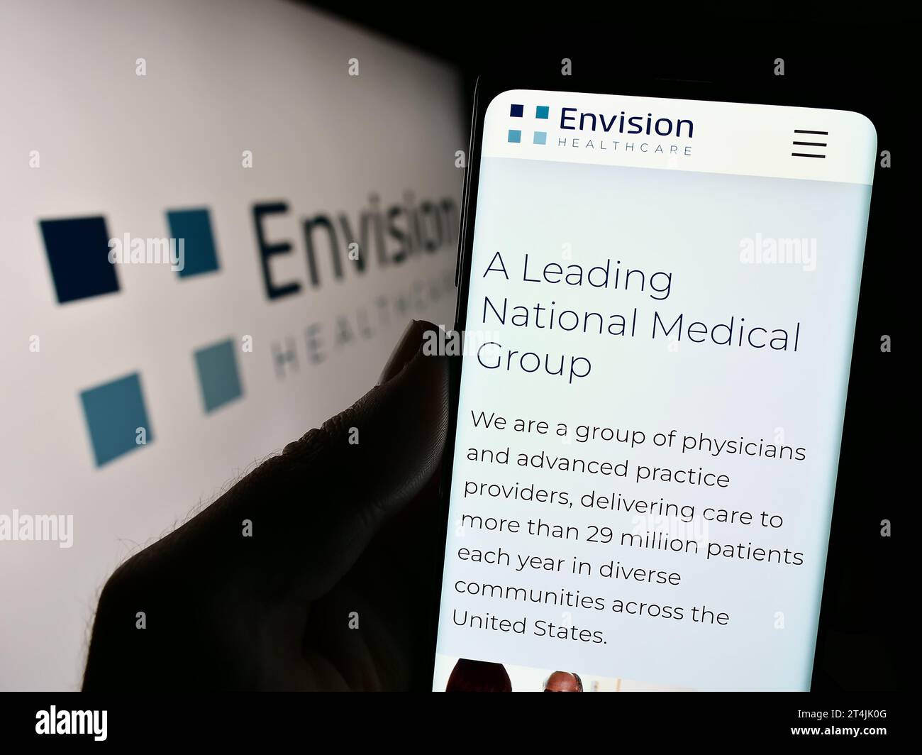 Person holding cellphone with website of US hospital company Envision ...