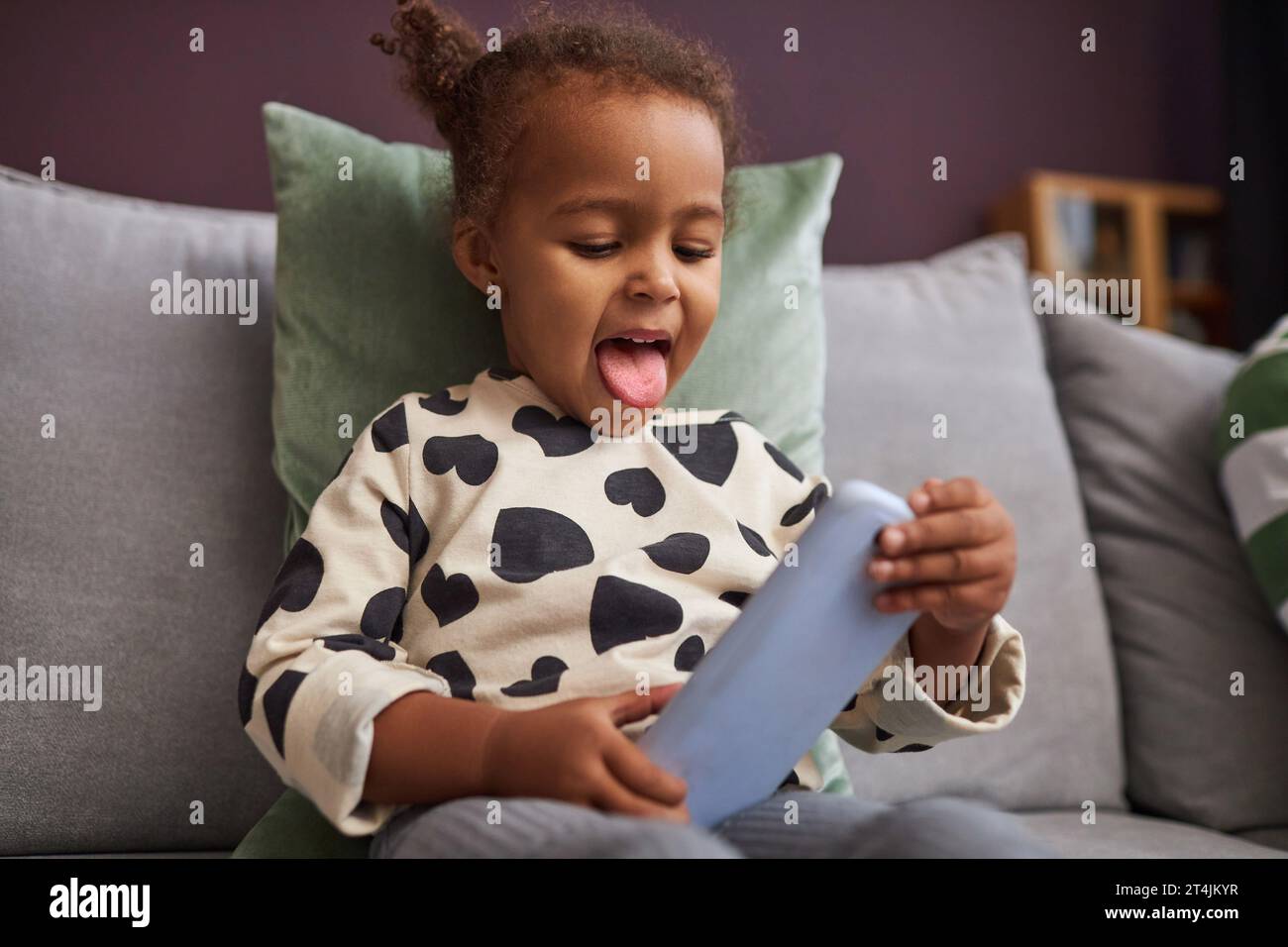 Portrait of curious little girl holding smartphone and playing mobile games for children Stock Photo