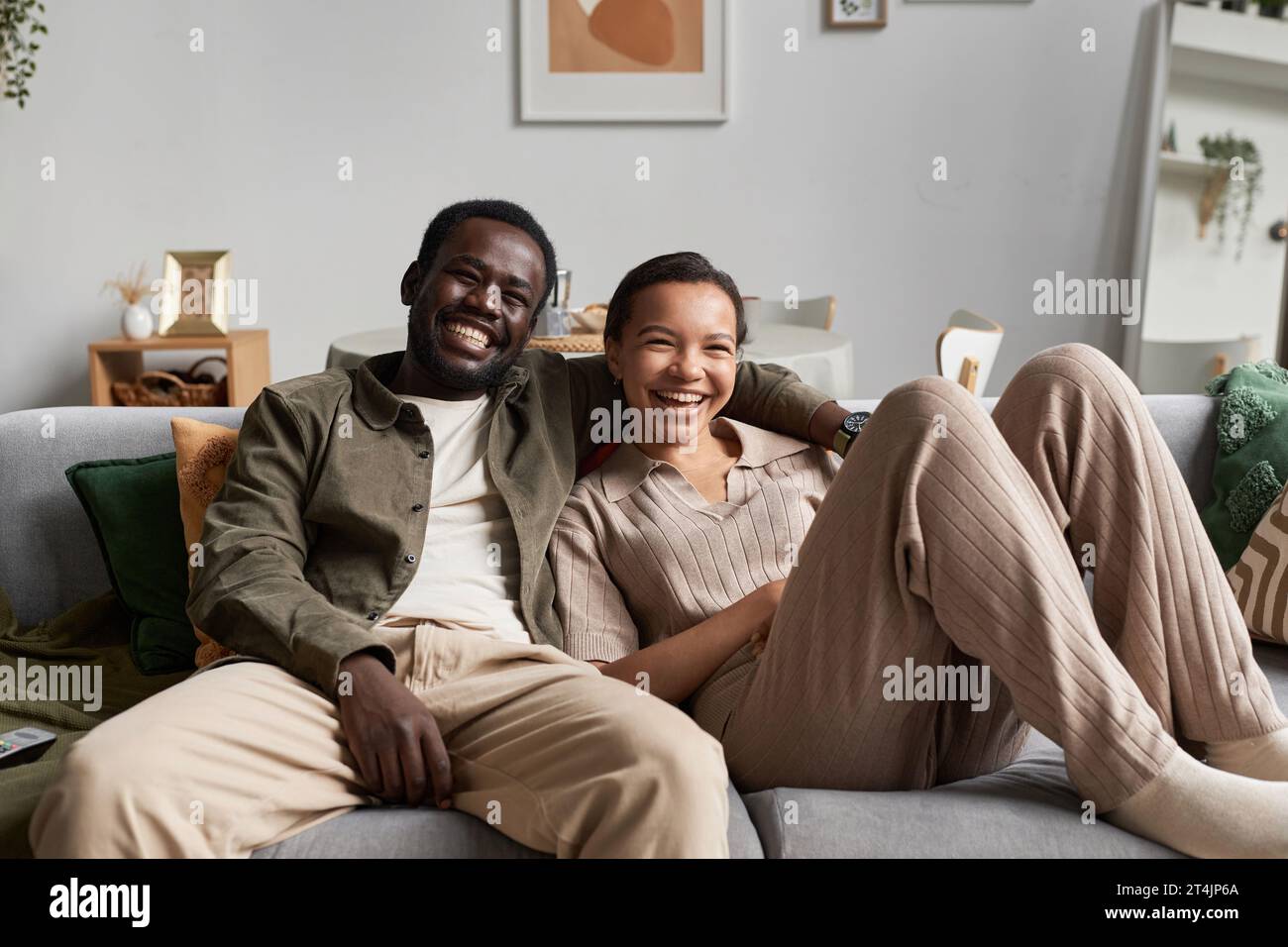 Portrait of young African American couple watching Tv together and ...
