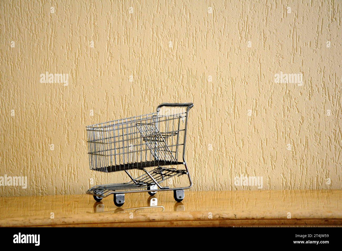 Empty supermarket cart with travertine marble base and wall with graffiti in the background Stock Photo