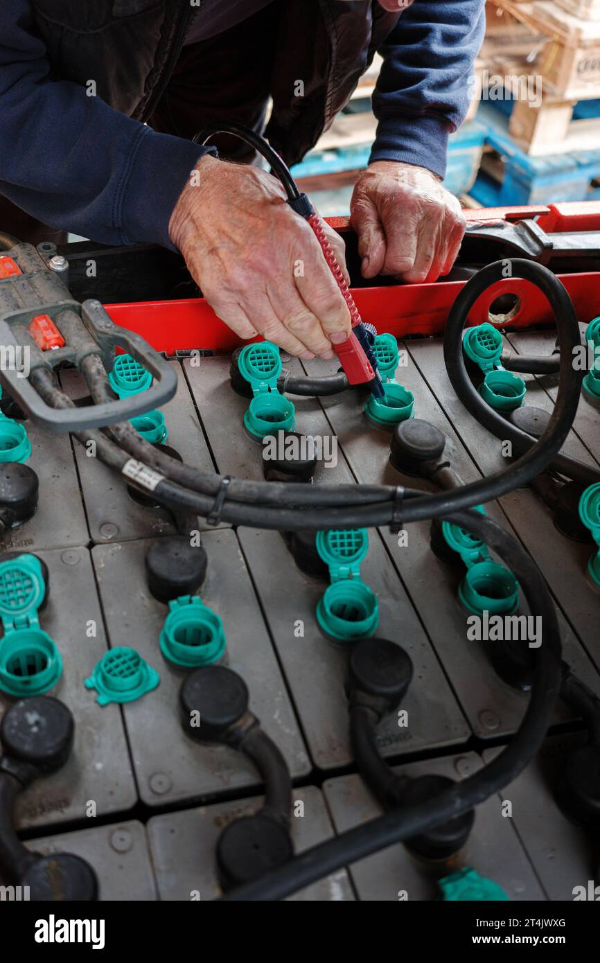 Forklift truck electric batteries being topped up at the regular maintenance check mans hand closeup with water hose topping up levels Stock Photo