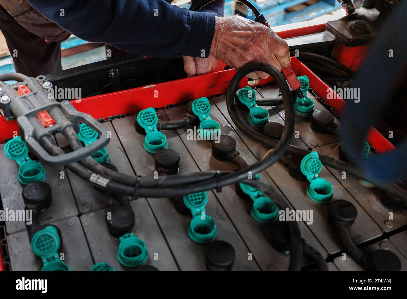Forklift truck electric batteries being topped up at the regular maintenance check mans hand closeup with water hose topping up levels Stock Photo
