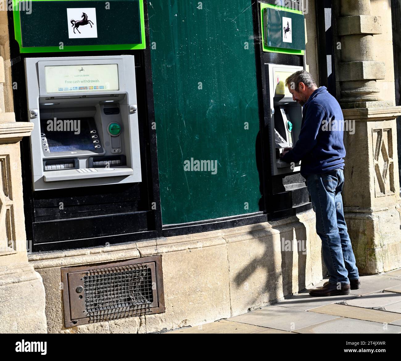 Man at ATM Lloyds cash machine with second machine free, city street Oxford, UK Stock Photo