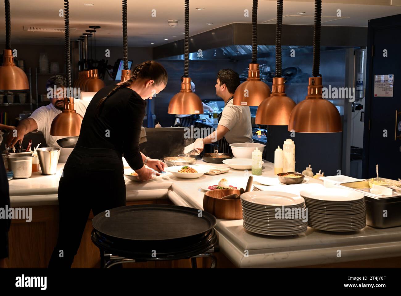 Restaurant chefs serving area with waitress collected food which is ready, Gusto Italian, Oxford, UK Stock Photo