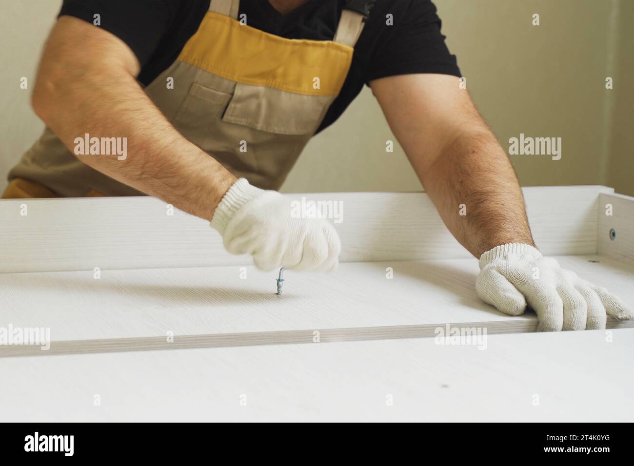 Furniture assembly. A worker fastens the parts of a bed using confirmat ...