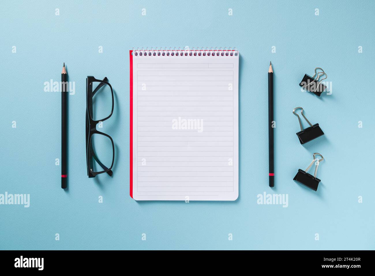 Top view of empty notebook, glasses, and pen on blue office desk Stock Photo