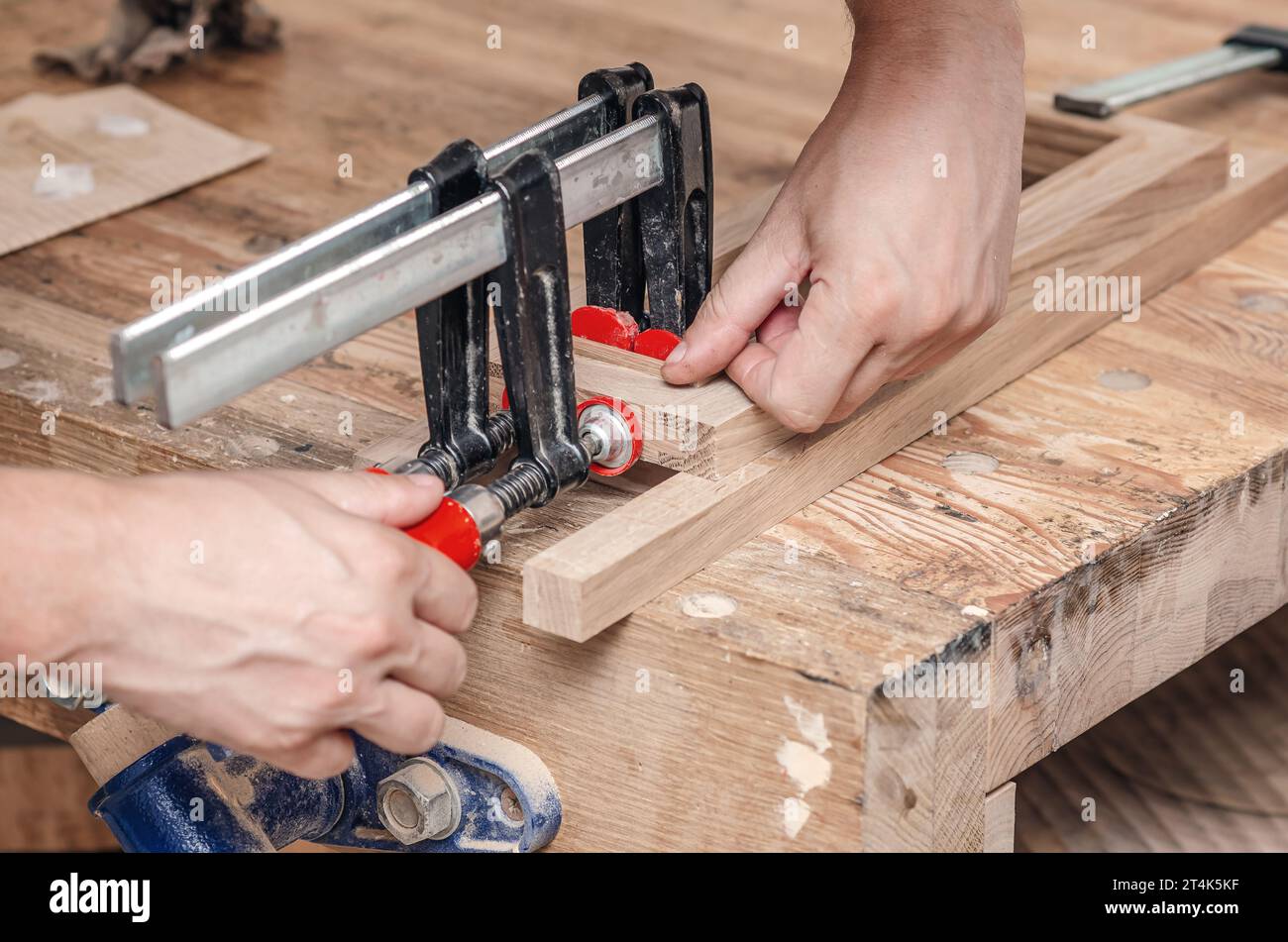 Carpenter clamps are fixed to boards. Gluing joinery in the workshop Stock Photo