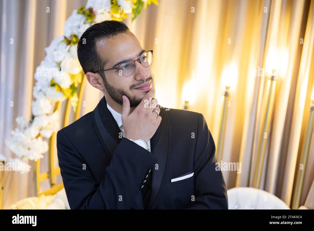 portrait for male wearing wedding tuxedo with flowers and lights in his background for celebration Stock Photo
