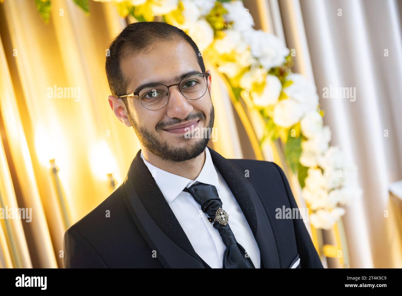 portrait for male wearing wedding tuxedo with flowers and lights in his background for celebration Stock Photo
