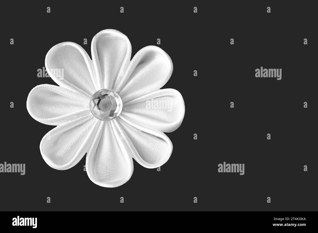 Handmade white fabric flower (kanzashi) isolated on dark grey background with copy space Stock Photo