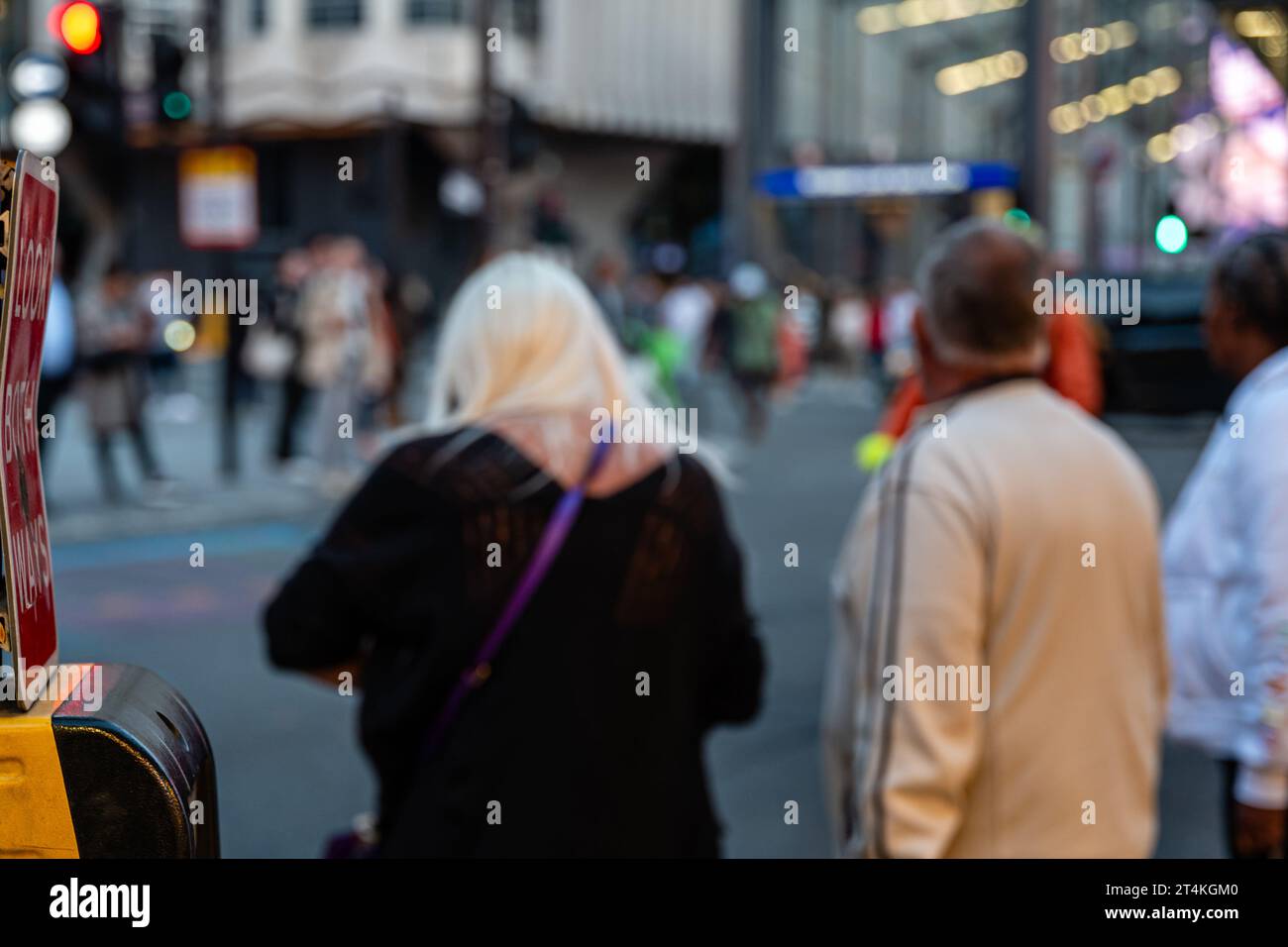 Some pedestrians are waiting to cross New Oxford Street in the London Borough of Camden, UK. Stock Photo