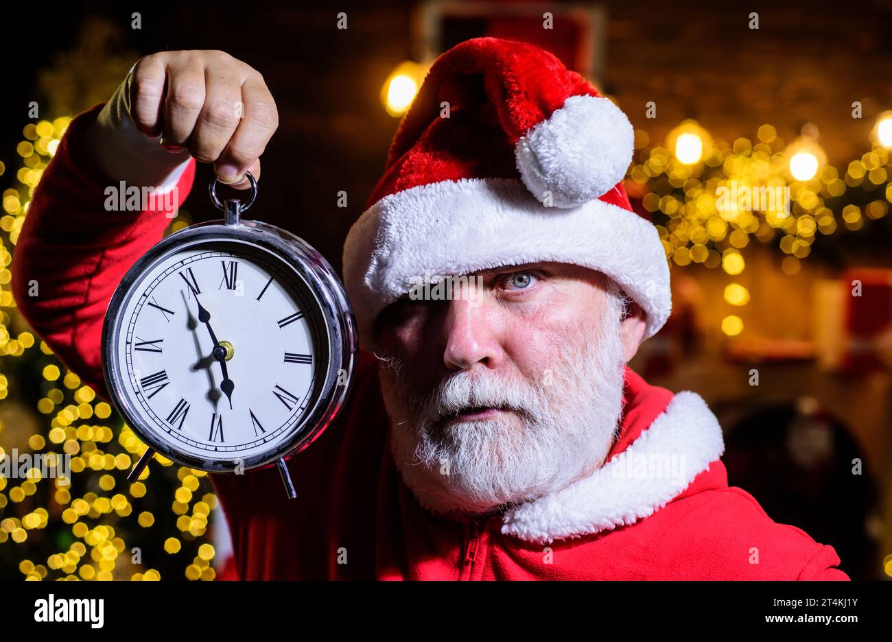 Merry Christmas and Happy New Year. Santa Claus with alarm clock. Santa celebrate Christmas. New year party. Winter holidays. Serious bearded man in Stock Photo