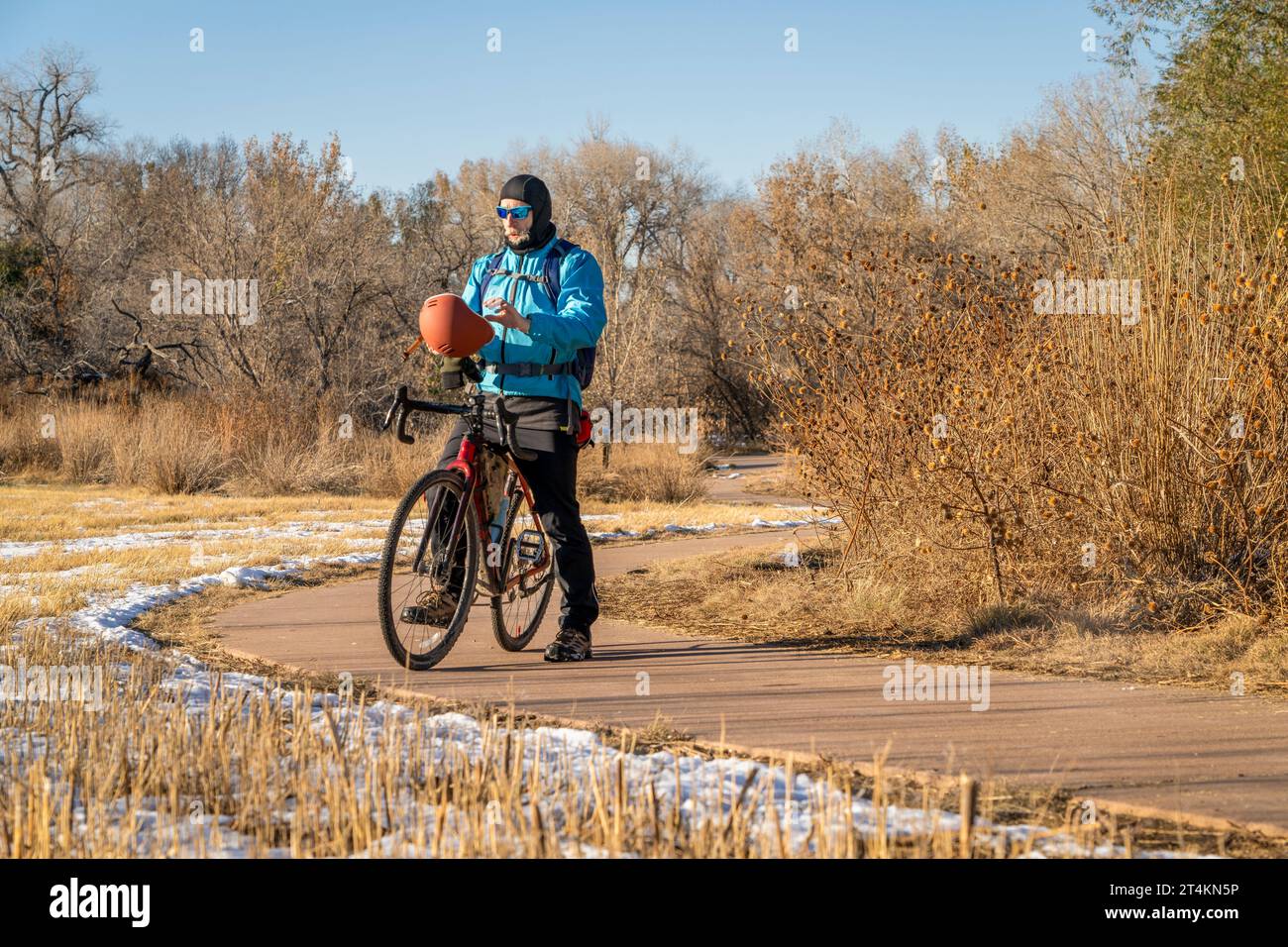 senior male cyclist with a touring gravel bike on a biking trail in Fort Collins, Colorado in cold fall weather with some snow Stock Photo
