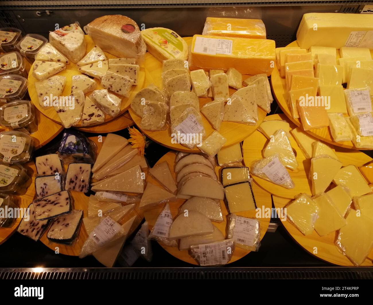 A retail display featuring a variety of cheeses in a variety of forms