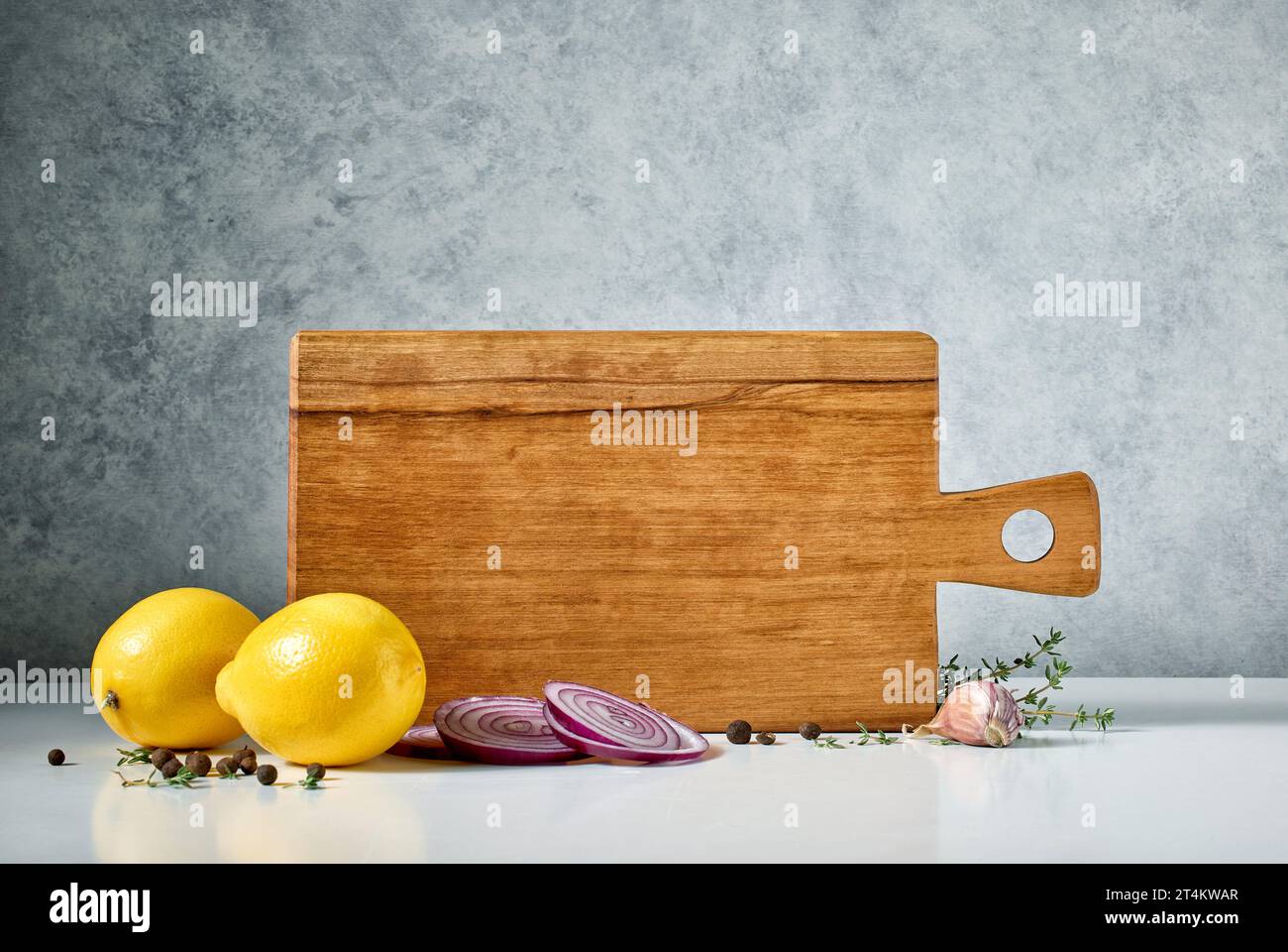still life with wooden cutting board and spices on grey background Stock Photo