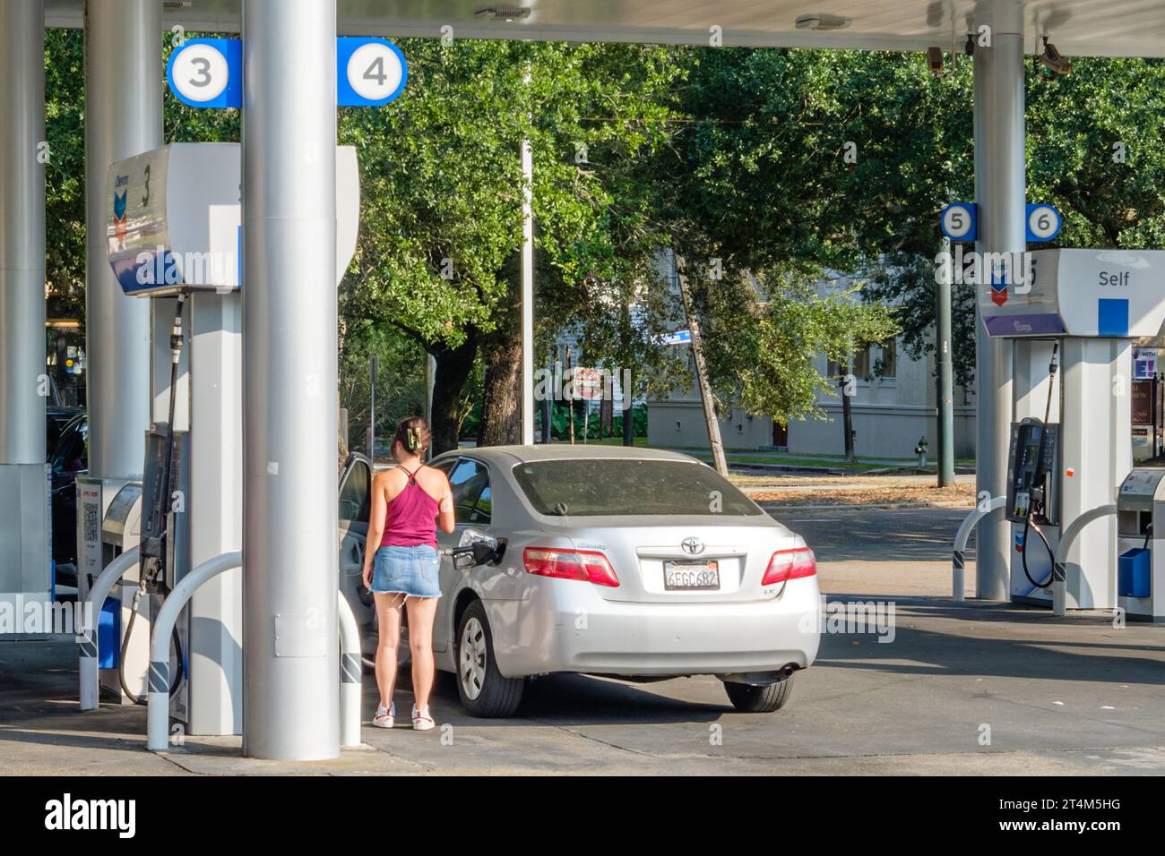 NEW ORLEANS, LA, USA - AUGUST 18, 2023: Young woman filling the gas tank of her car at a Chevron Station in the Carrollton Neighborhood Stock Photo