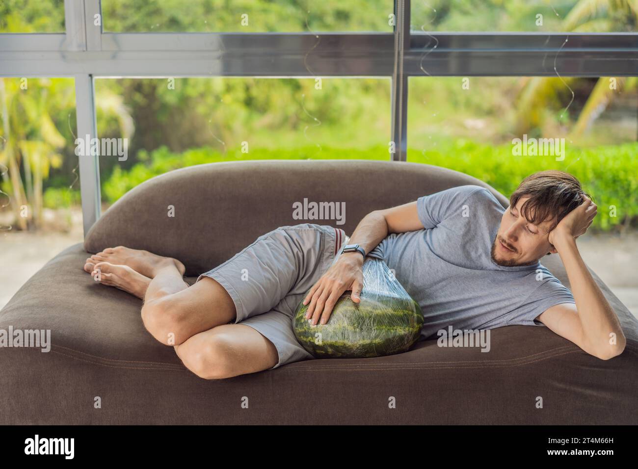 A humorous image: a pregnant woman and her husband playfully use a watermelon in place of a belly, comically highlighting the challenges of navigating Stock Photo