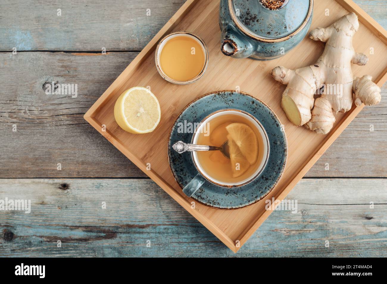 Ginger tea with lemon and honey in a blue cup on a bamboo tray on a wooden background, top view Stock Photo