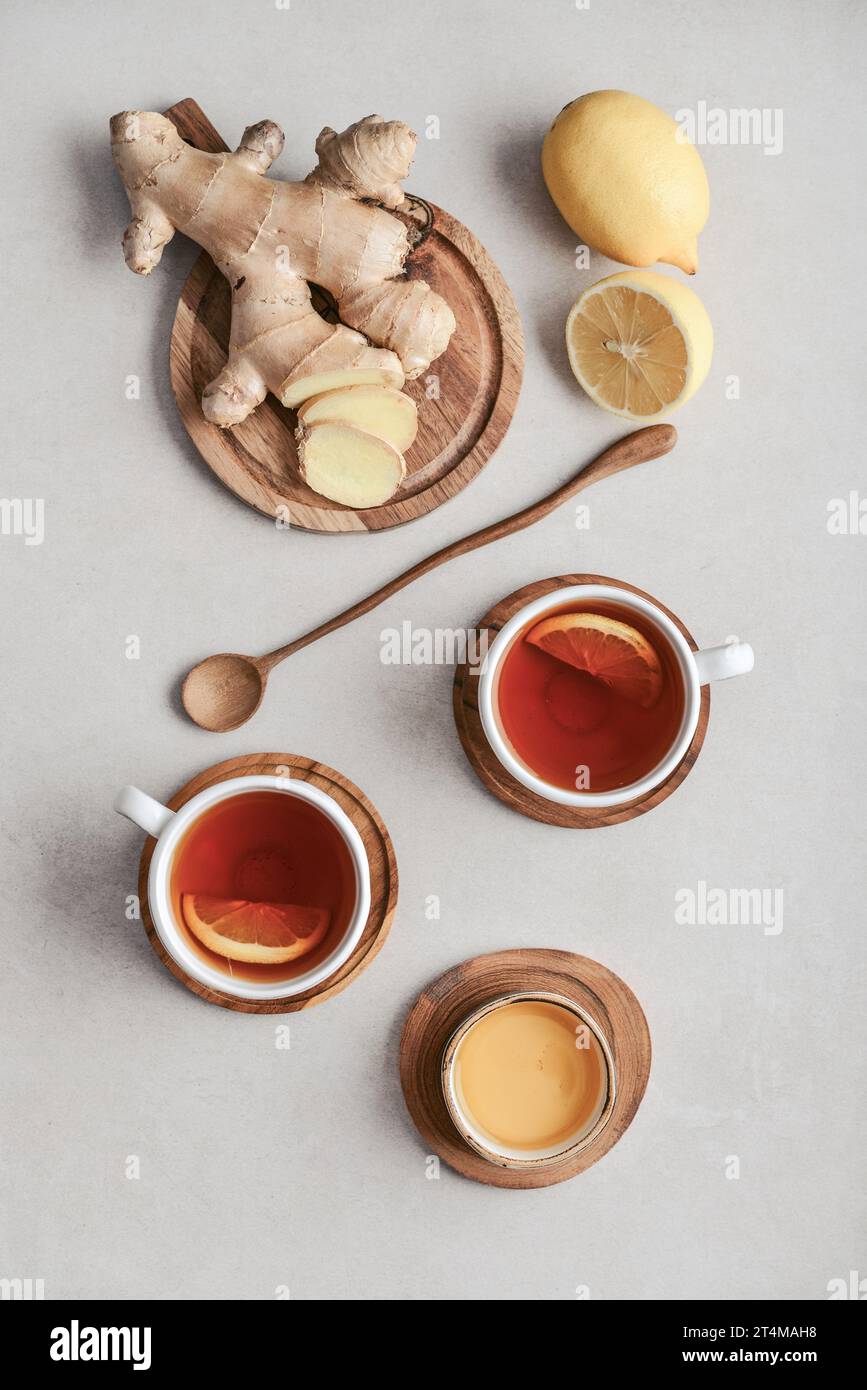 Tea  in a white cups with lemon, ginger root on cutting board and  and honey  on a light background, top view Stock Photo