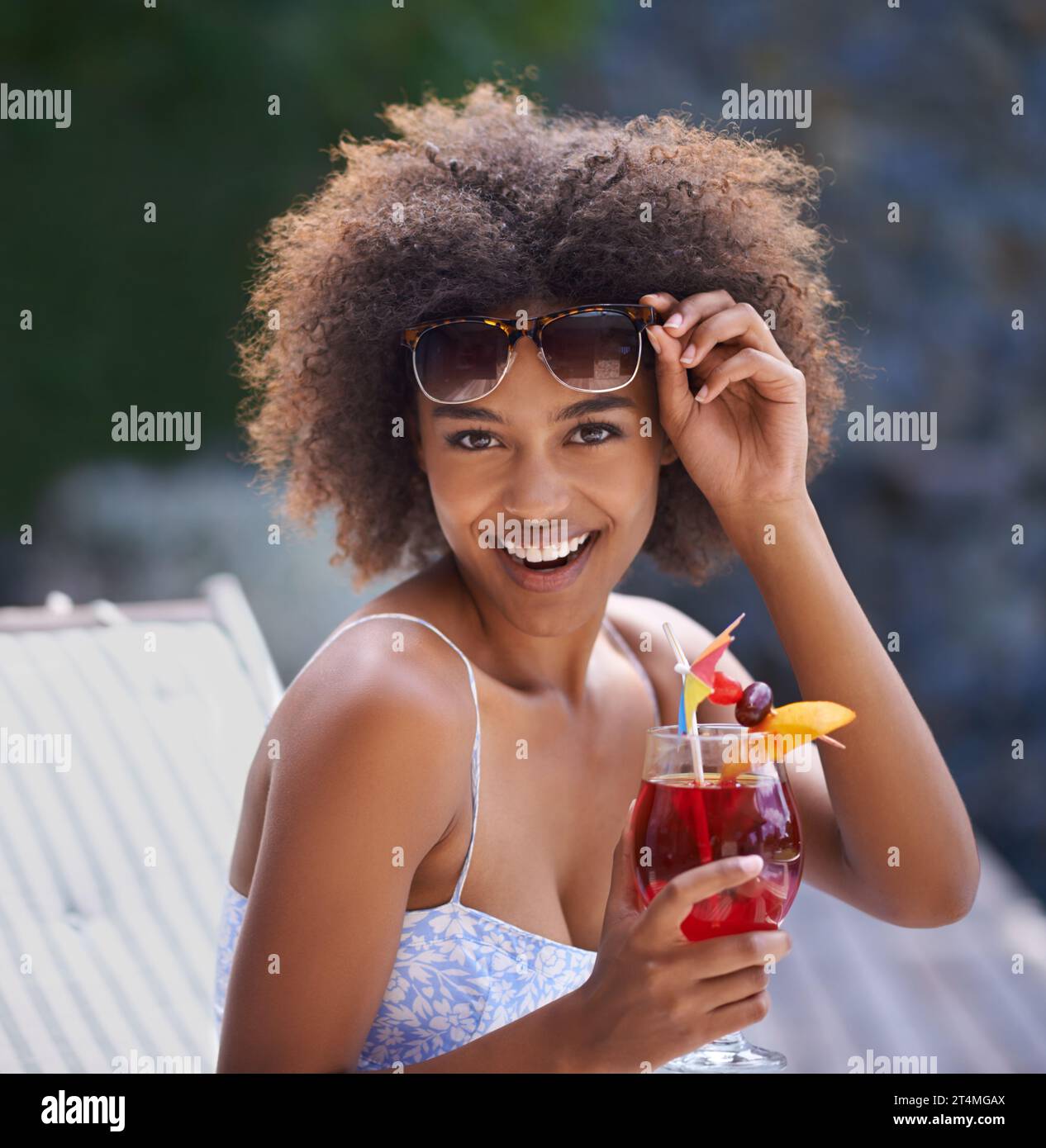 Loving the cocktails and sunshine. Attractive ethnic female posing with sunglasses and fruity cocktail. Stock Photo