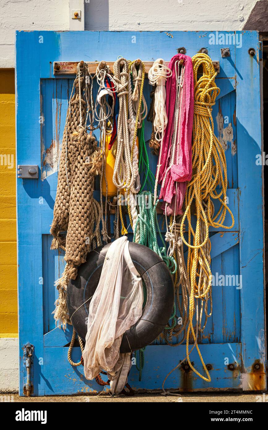 Coiled maritime ropes used in sailing hang on a boat shed door Stock Photo
