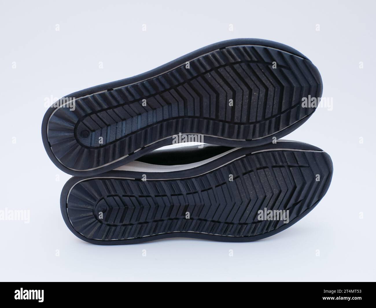 the bottom surface of a pair of black shoes. black rubber shoe soles of male, tread, base, foot step, foot print. Stock Photo