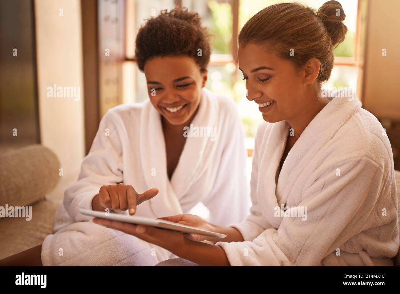 Lets get this therapy started...two friends in bathrobes using a digital tablet at a spa. Stock Photo